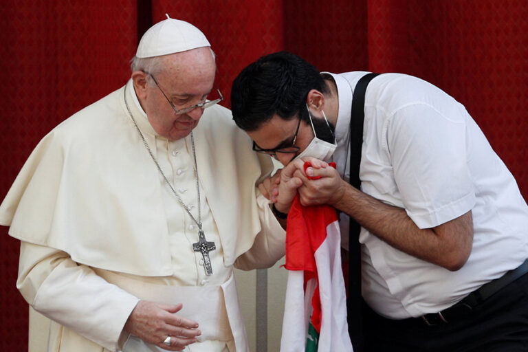 A masked Maronite Father Georges Briedi kisses the hand of Pope Francis