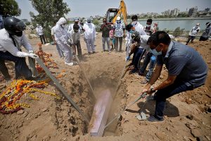 People lower the body of a man who died of COVID-19 into a grave at a cemetery in Ahmedabad, India.