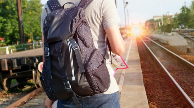 person with a backpack shown from behind with sunburst ahead