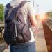 person with a backpack shown from behind with sunburst ahead