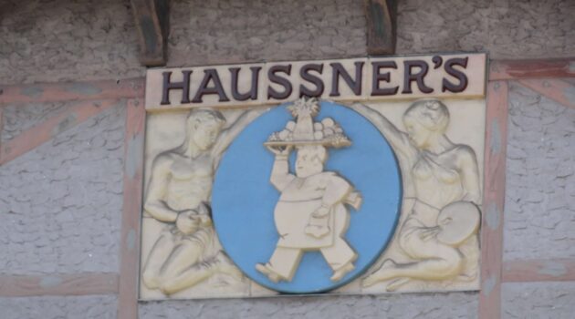 Sculpture relief with Haussner's printed on it and a man carrying a platter of food