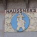 Sculpture relief with Haussner's printed on it and a man carrying a platter of food