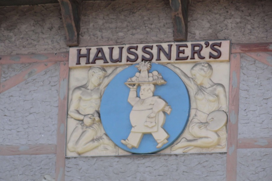 Sculpture relief with Haussner's printed on it and a man carrying a platter of food