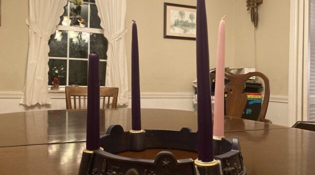 Four unlit candles stand in an Advent wreath on a table