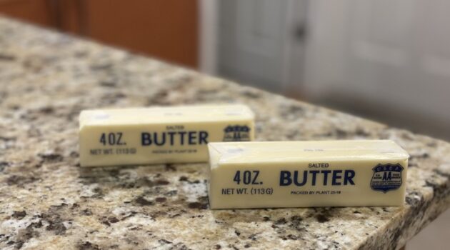 Two sticks of butter sit on a kitchen counter