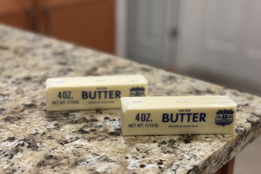 Two sticks of butter sit on a kitchen counter