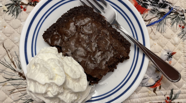 Brownie on a plate with whipped cream a fork