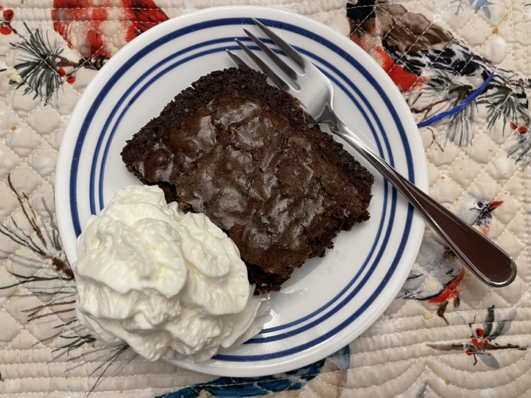 Brownie on a plate with whipped cream a fork