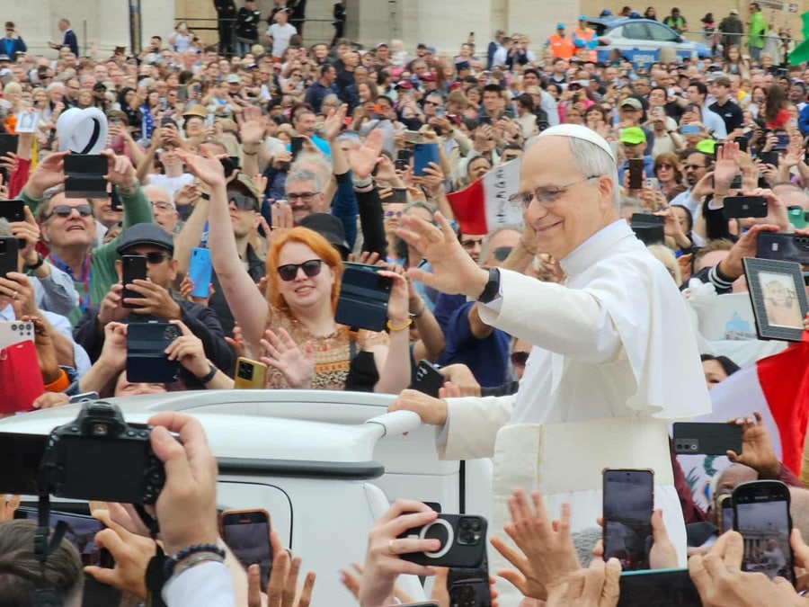 A smiling Pope Leo waves to a crowd in St. Peter's Square
