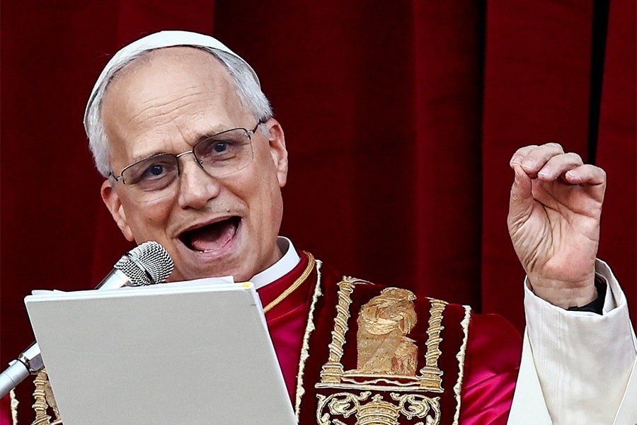 Pope Leo smiles as he speaks into a microphone