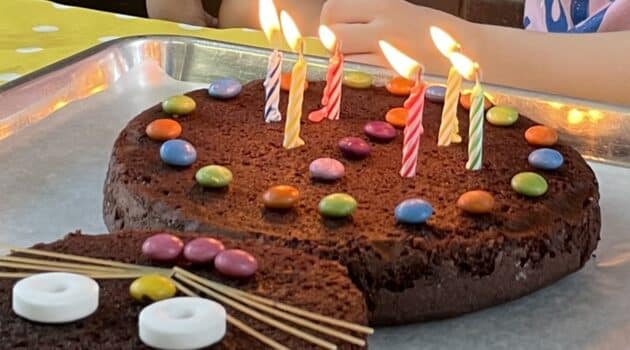 Six lit candles on a chocolate birthday cake