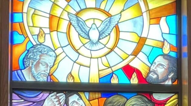 Stained glass window depicting a dove and some of the apostles with flames over their heads