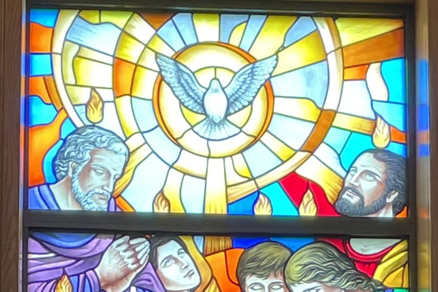 Stained glass window depicting a dove and some of the apostles with flames over their heads