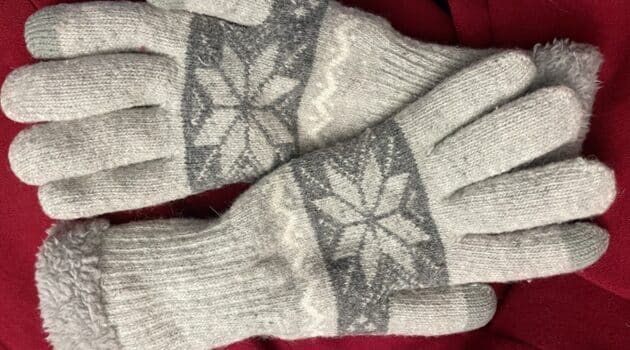 Gray and white gloves rest on part of a red coat