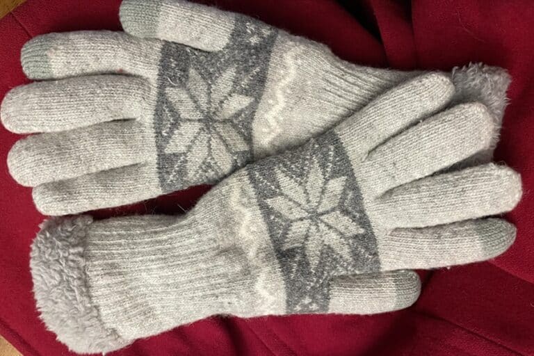 Gray and white gloves rest on part of a red coat