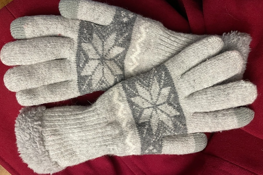 Gray and white gloves rest on part of a red coat