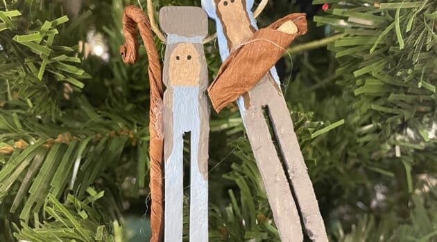 Clothespin ornaments depicting Joseph, Mary, and Baby Jesus hang on a Christmas tree