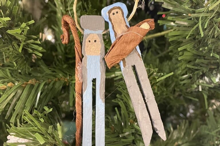 Clothespin ornaments depicting Joseph, Mary, and Baby Jesus hang on a Christmas tree