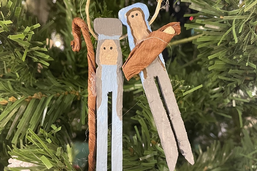 Clothespin ornaments depicting Joseph, Mary, and Baby Jesus hang on a Christmas tree