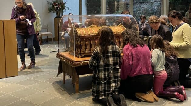 People kneel around St. Therese's relics in the chapel at the Carmelite Monastery