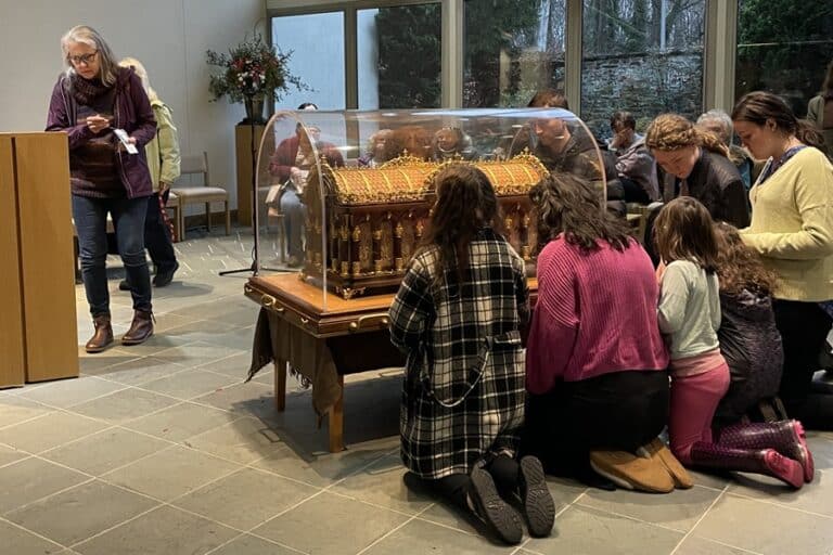 People kneel around St. Therese's relics in the chapel at the Carmelite Monastery