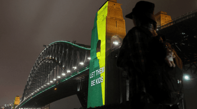 A message the reading "Let them be kids" is projected onto the Sydney Harbor Bridge