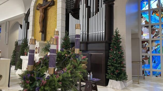 Four candles lit on Advent wreath on the altar in a church