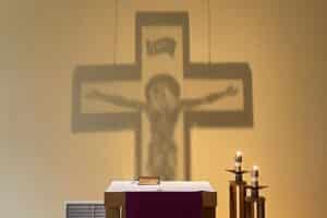 The shadow of a crucifix is shown on the wall of a chapel