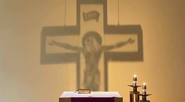 The shadow of a crucifix is shown on the wall of a chapel