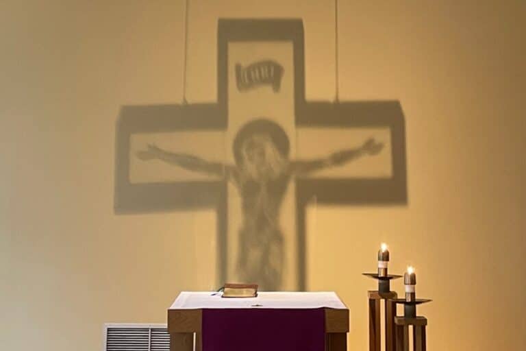 The shadow of a crucifix is shown on the wall of a chapel