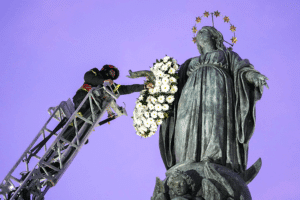 Roberto Leo, a senior firefighter, places a wreath of flowers on a Marian statue