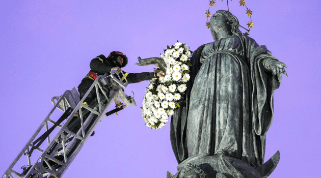Roberto Leo, a senior firefighter, places a wreath of flowers on a Marian statue