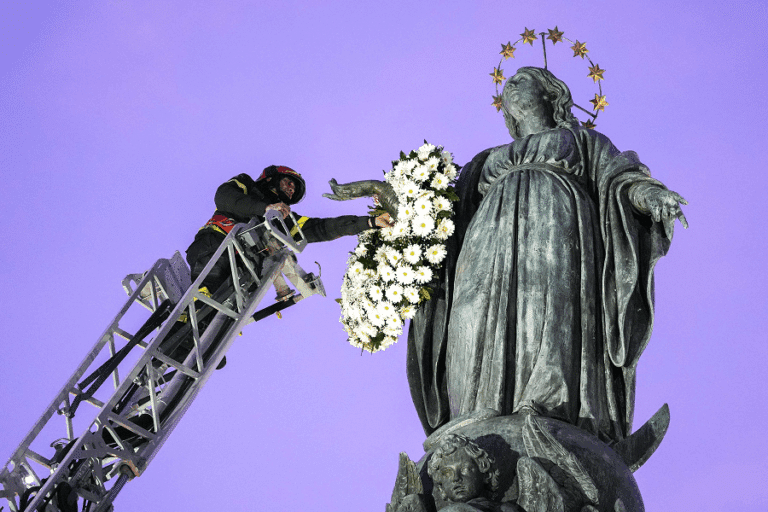 Roberto Leo, a senior firefighter, places a wreath of flowers on a Marian statue