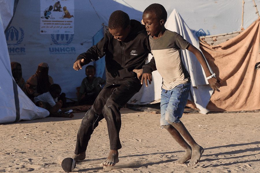 Sudanese refugee children from al-Fashir play with each other with a handmade sock ball at the Tine transit refugee camp