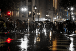 People holding umbrellas in the rain attend a protest against U.S. Immigration and Customs Enforcement