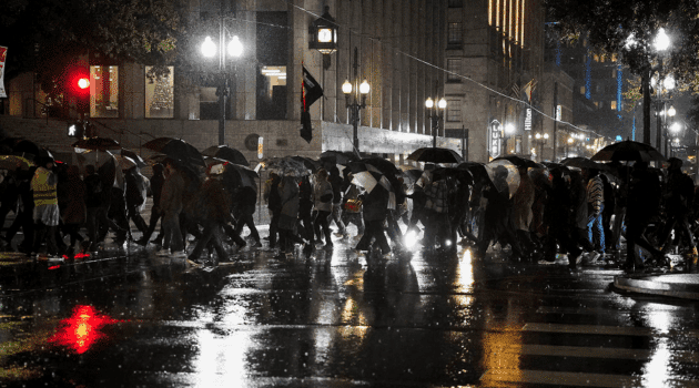 People holding umbrellas in the rain attend a protest against U.S. Immigration and Customs Enforcement