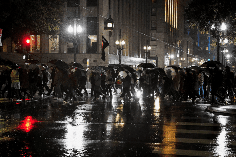 People holding umbrellas in the rain attend a protest against U.S. Immigration and Customs Enforcement