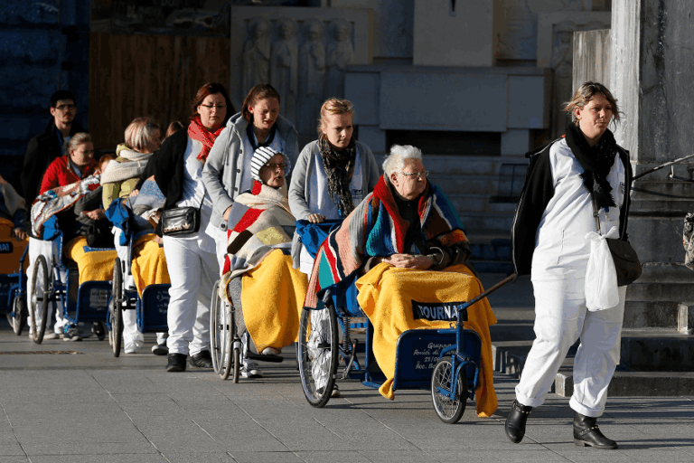 Caregivers push the sick and disabled at the Shrine of Our Lady of Lourdes