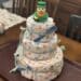 A tower of diapers with baby toys tied on and a rubber duck on top