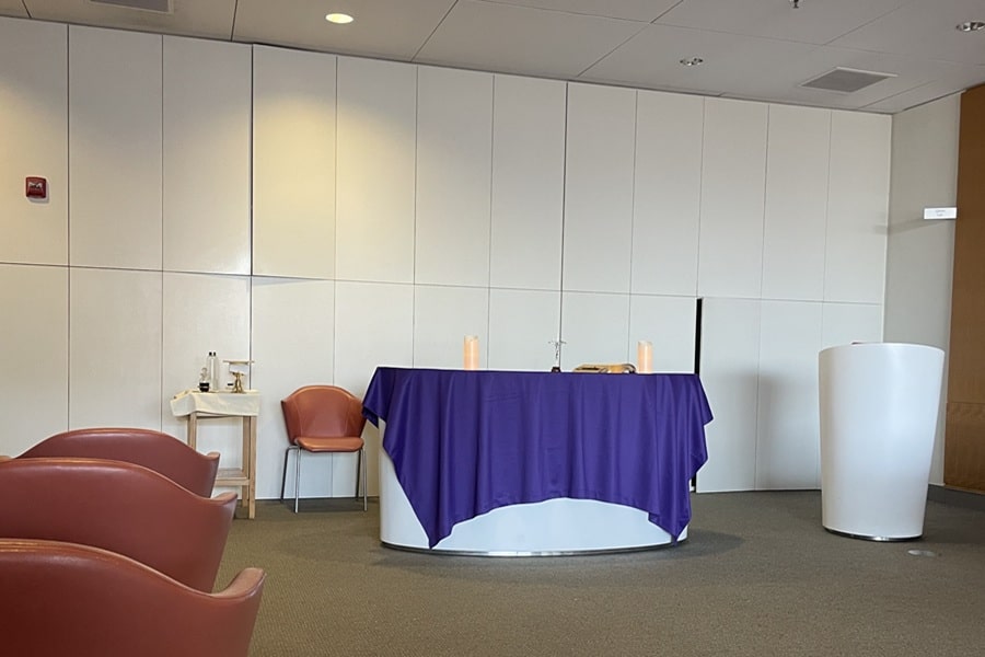 A purple cloth covers an altar against a white wall in the front of a room