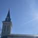 Church steeple against a blue sky with the shining sun