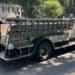 Firefighter rides on the back of a vintage fire engine