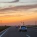 A car drives on a road at sunset