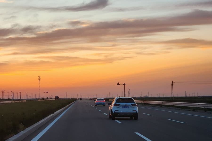 A car drives on a road at sunset