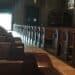 Pews in a church with sunlight streaming through the main door at the center