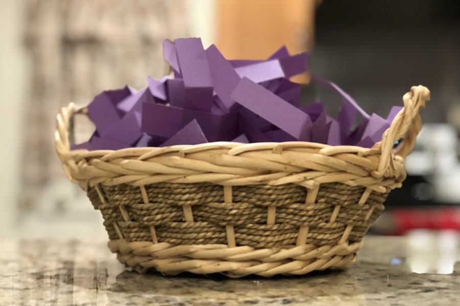 A basket of purple slips of paper sits on a counter