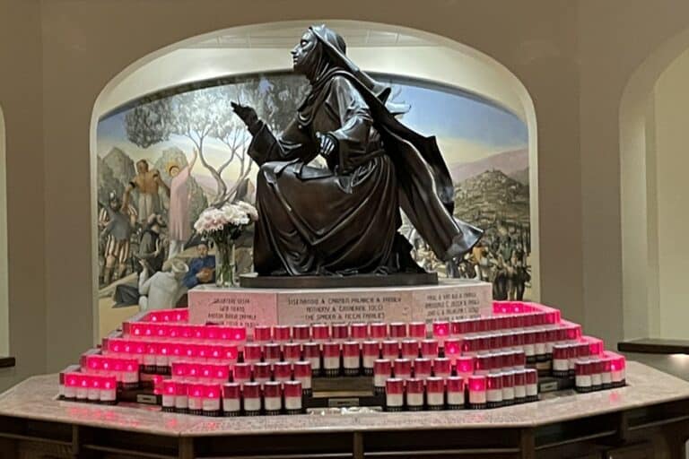 St Rita statue surrounded by red candles